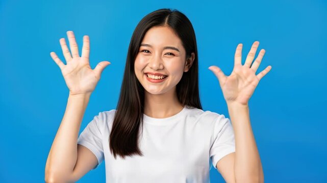 Smiling Woman Showing Ten Fingers: A young Asian woman with long black hair and a bright smile, wearing a white t-shirt.