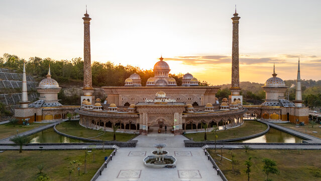 Aerial view of the ornate Samin Baitul Muttaqin Mosque with its golden domes and tall minarets surrounded by landscaped gardens and reflecting pools in Bojonegoro, East Java, Indonesia.