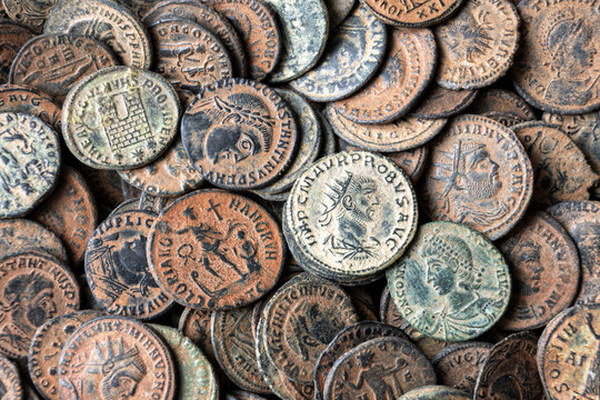Close-up of collection of ancient Roman bronze coins. Top view of money hoard with emperor portraits and Latin inscriptions. Archaeology and historical background concept