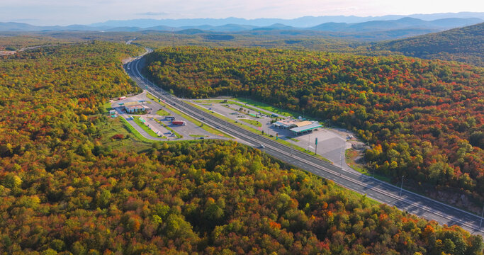 Otocac, Croatia, 22nd October 2025: AERIAL: Motorway rest area and gas station surrounded by colourful autumn forest. Service stops along winding highway while driving through scenic landscape in fall