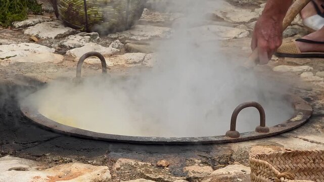 Close up shot of dipping and lifting a wire mesh basket full of green grapes in a steaming boiling cauldron during the Escalda festival in Spain. Traditional grape scalding process (l'escald&agrave;) for art