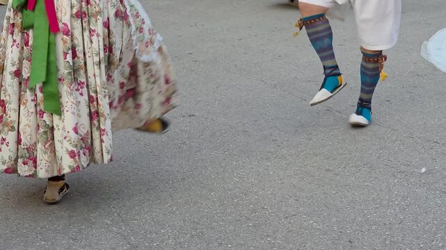Low angle close up shot of legs of dancers wearing traditional Valencian costumes and espadrilles performing folk dance during a cultural festival in Teulada, Spain. Dynamic footage 
