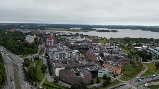 aerial drone video of the Arabianranta residential area in Helsinki, Finland, featuring modern buildings, green spaces, streets, and the surrounding urban landscape during summer.