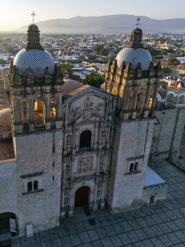 Aerial view of the historic Santo Domingo de Guzman Church with its iconic tiled domes and stone facade illuminated by the soft morning light in Oaxaca, Oaxaca, Mexico.