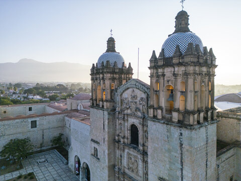 Aerial view of the historic Templo de Santo Domingo de Guzman with its iconic tiled domes and twin bell towers illuminated by soft morning light in Oaxaca, Oaxaca, Mexico.