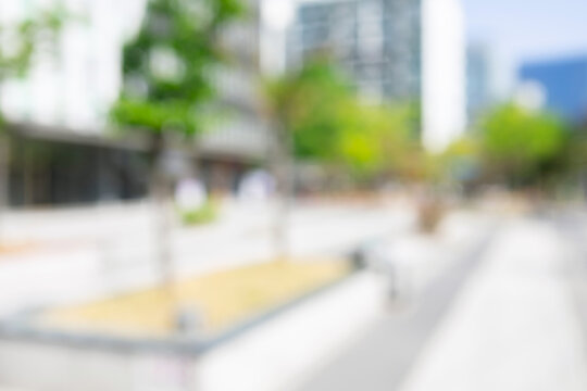 Abstract blurred modern urban plaza background with a building frontage and green trees