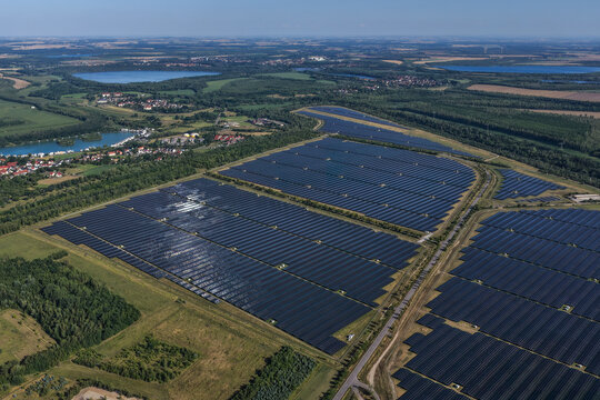 Aerial view of a large-scale solar park with rows of photovoltaic panels situated in the renatured open pit coal mines of Leipziger Neuseenland, Leipzig, Saxony, Germany.