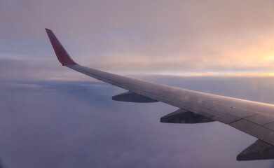 Fototapeta premium Beautiful salmon dawn and the wing of an airplane above the clouds.