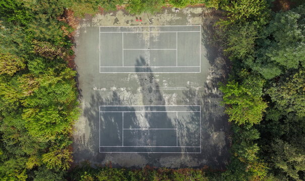 Aerial view of two tennis courts surrounded by lush green trees in Pancevo, Vojvodina, Serbia.