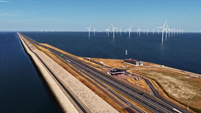 Aerial view follows the Afsluitdijk highway across open water toward the offshore wind turbines of Windpark Fryslan near Breezanddijk Netherlands