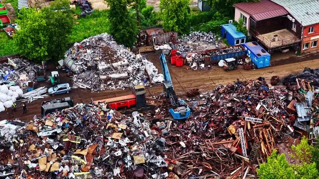 Aerial view of scrap metal junkyard with material handler crane and recycling piles.