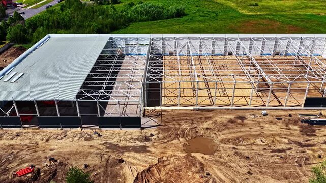 aerial view of a steel framing and roof installation on industrial building construction site.