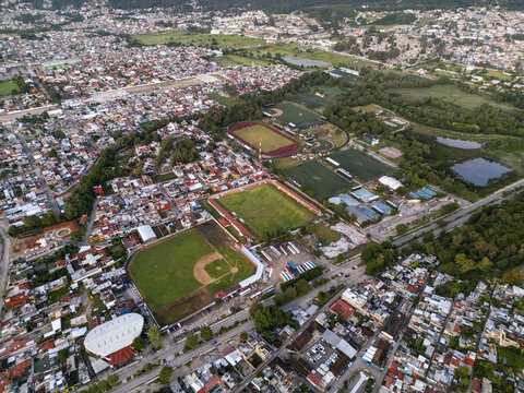 Aerial view of sports facilities including baseball and soccer fields surrounded by urban residential areas in San Cristobal de las Casas, Chiapas, Mexico.