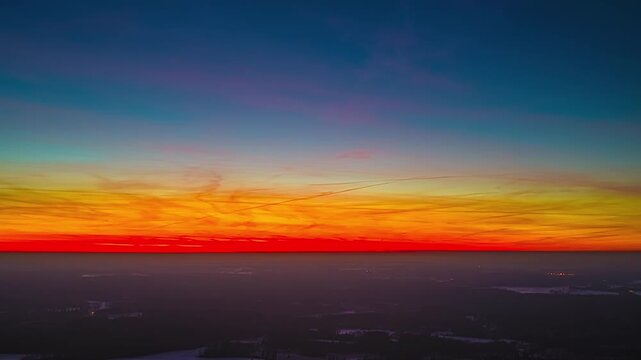 A Breathtaking Sunset Paints the Horizon With Vibrant Shades of Red, Orange, and Blue Above the Distant Landscape - Hyperlapse
