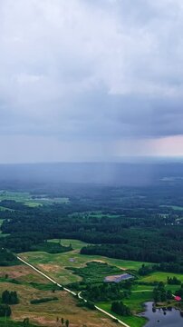 distant rain shaft and heavy storm clouds rolling over a vast countryside landscape.