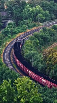 Coal freight train curves through dense greenery near RWE power infrastructure in Germany