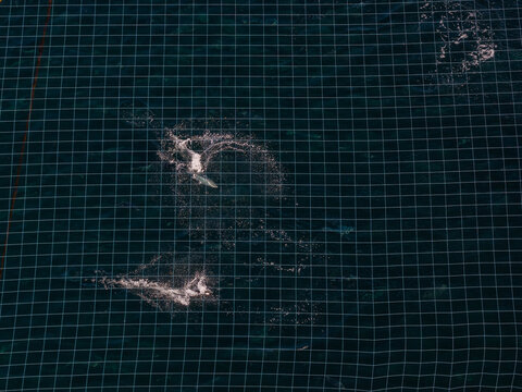 Aerial view of a fish farm net submerged in deep blue water with salmon splashing on the surface in Liabygda, More og Romsdal, Norway.