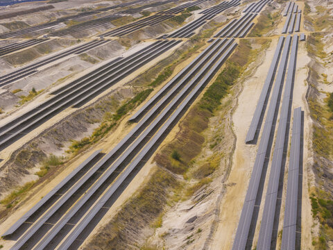 Aerial view of a large-scale solar farm installed within the terraced landscape of an open-pit brown coal mine in Germany.