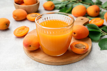 Apricot juice in glass, fresh fruits and leaves on light table, closeup © New Africa