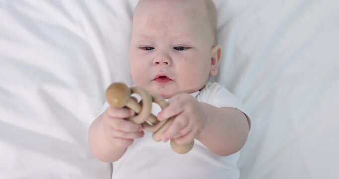 Cute little baby with teether on bed at home, top view. Camera moving in