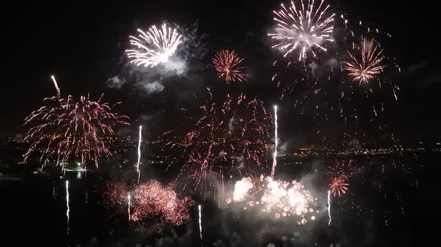 Aerial view of colorful fireworks exploding in the night sky above the coastal town of Cascais, Lisbon, Portugal.
