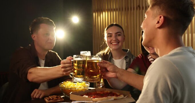 Happy friends eating snacks and drinking beer indoors