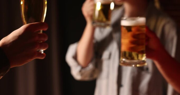 Friends clinking glasses of beer indoors, closeup. Camera moving in and up