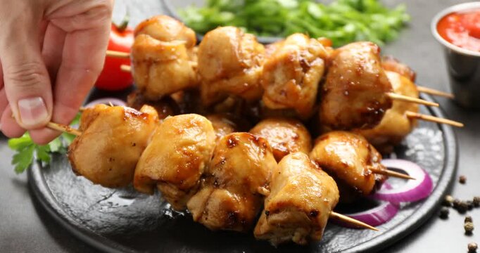 Man taking delicious shish kebabs at grey table, closeup