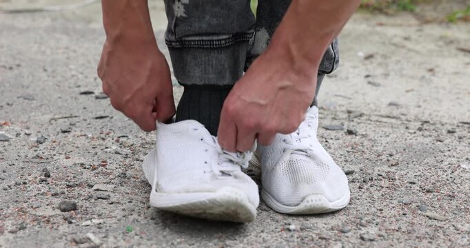Poor man in shabby sock wearing old sneaker outdoors, closeup