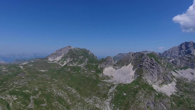 Aerial view of the rugged Bobotov Kuk mountain peak surrounded by green slopes and rocky terrain in Zabljak Municipality, Montenegro.