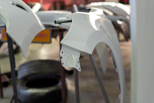 Freshly painted white car fender mounted stand inside an automotive body shop during vehicle repair refinishing restoration work