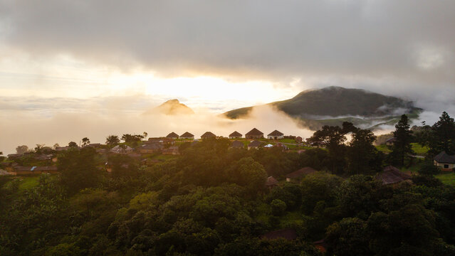 Aerial view of Obudu Mountain Resort nestled among lush green hills and rolling mountains under a golden sunrise with clouds drifting through the landscape Obudu, Cross River, Nigeria.