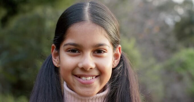 Indian girl child spotting camera lens shifting into smile then bursting into laughter in park