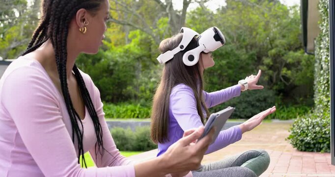African American coach guiding VR user wearing headset after tapping tablet swiping panels on patio