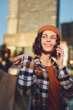woman shopping smartphone smile city candid young woman shopping on a city street, talking on smartphone with smile during golden hour glow, authenticity and mindful living, emotional storytelling