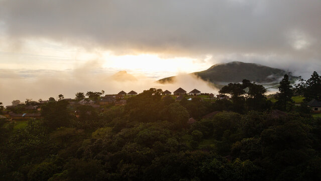 Aerial view of Obudu Mountain Resort nestled among lush green hills and rolling clouds at sunrise in Obudu, Cross River, Nigeria.