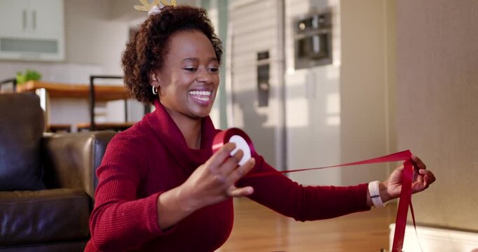 Mature woman pulling red ribbon on floor, friend handing scissors and cutting for Christmas