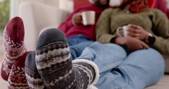 Camera pulling back, African American couple leaning on sofa, holding mugs, celebrating Christmas