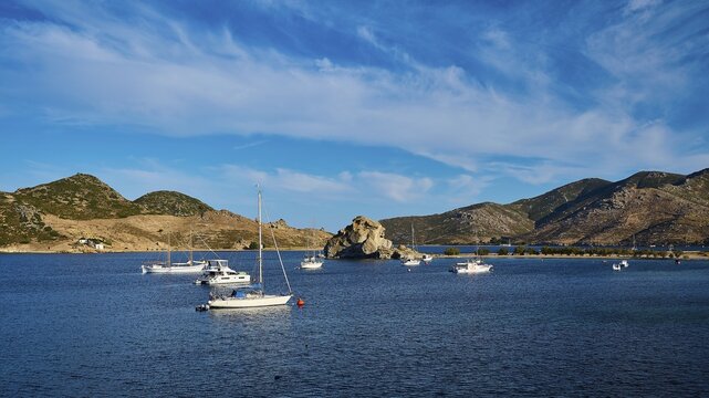 Boats on calm blue water, surrounded by mountains and rocks under a cloudy sky, Petras Beach, Kalikatsou Rocks, Patmos, Dodecanese, Greek Islands, Greece