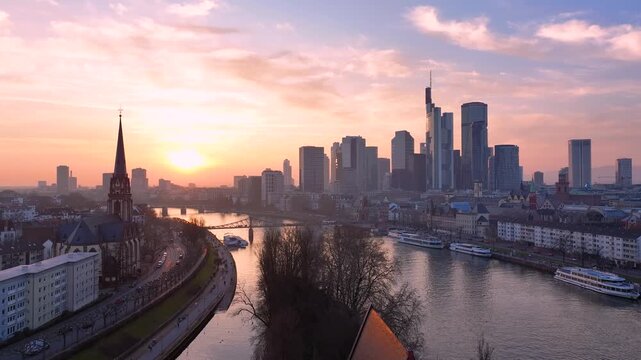 Aerial view of Dreikonigskirche and the modern skyscrapers of the Frankfurt skyline along the Main river at sunset in Frankfurt am Main, Hessen, Germany.