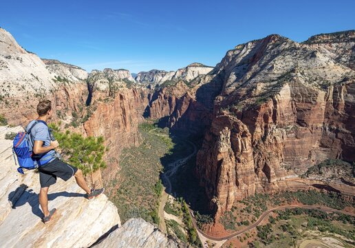 Young man, hiker standing at cliff, view from Angels Landing into Zion Canyon with Virgin River, Zion National Park, Utah, USA