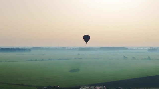 Lone balloon drifts above green fields as golden dawn illuminates rural Latvia