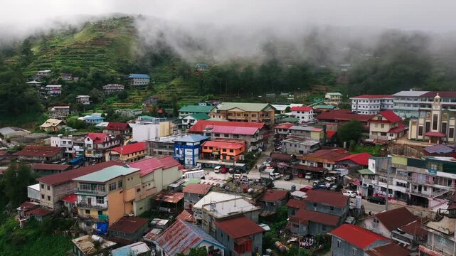 Low rain clouds drift above colorful mountain town homes in Atok, Benguet