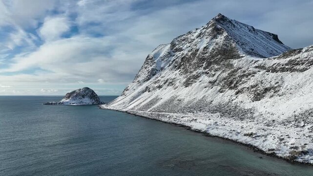 Aerial view of Haukland Beach with snow-covered mountains and deep blue sea in Leknes, Nordland, Norway.
