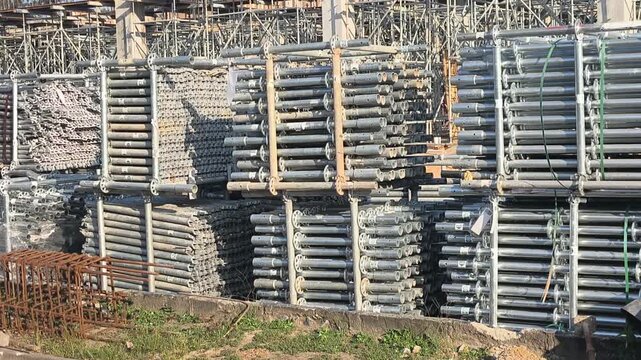 Neatly stacked modular scaffolding and formwork materials at a construction site. Modular Ringlock steel system ready for assembly on building projects. Essential structural support equipment.