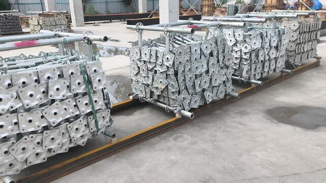 Neatly stacked modular scaffolding and formwork materials at a construction site. Modular Ringlock steel system ready for assembly on building projects. Essential structural support equipment.