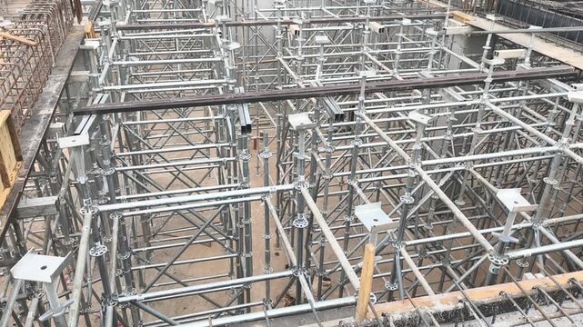 Neatly stacked modular scaffolding and formwork materials at a construction site. Modular Ringlock steel system ready for assembly on building projects. Essential structural support equipment.