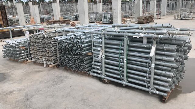 Neatly stacked modular scaffolding and formwork materials at a construction site. Modular Ringlock steel system ready for assembly on building projects. Essential structural support equipment.