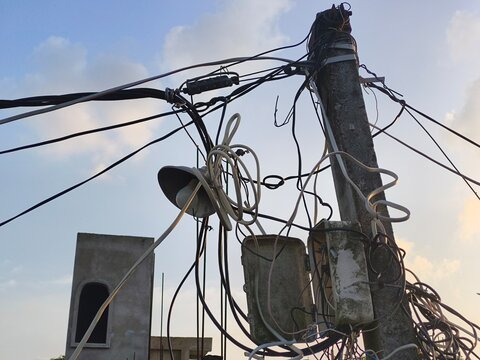 Messy tangled electrical wires and open junction box on electric pole