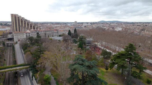 Urban park with mature trees and roads overlooking Montpellier city center, France, aerial